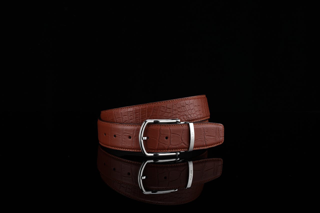 Stylish brown leather belt with crocodile texture on black background.